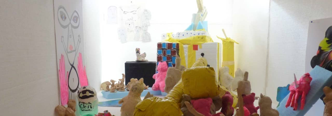 Viele farbige Skulpturen und Kunstwerke in einem weissen Raum.