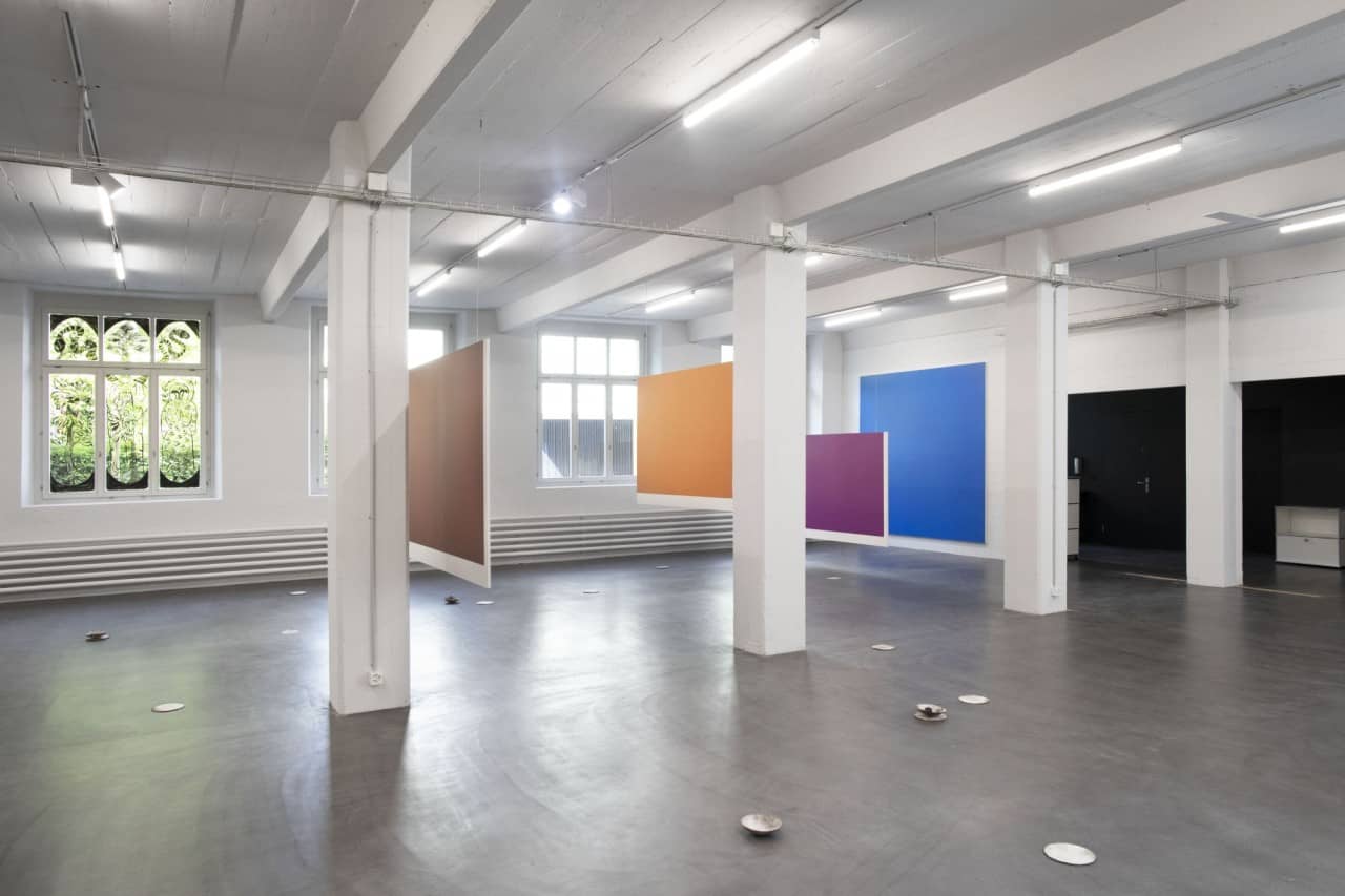Ein Ausstellungsraum. Es hängen farbige Bilder von der Decke