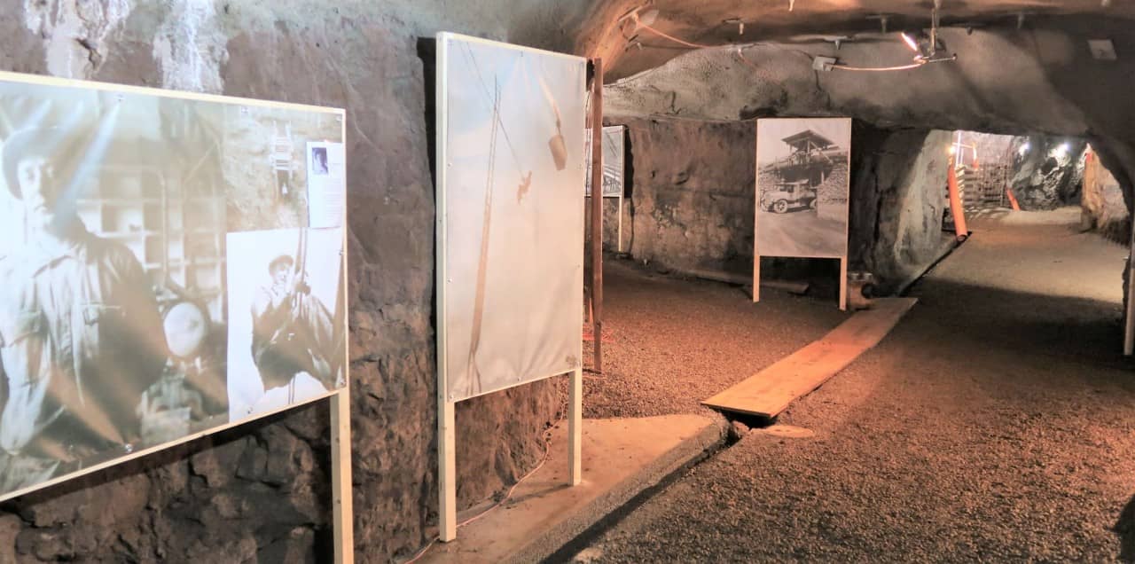 Fotoaufnahme des Stollens im Bergwerk Herznach, auf Infotafeln sind alte Fotografien zu erkennen. 