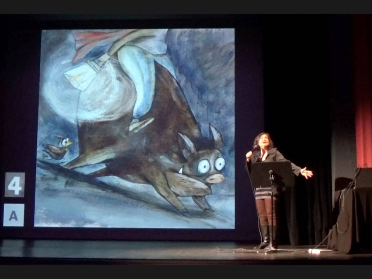 Eine Frau steht neben einer Projektion eines Bilds. Auf dem Bild ist ein Wildschwein abgebildet. 