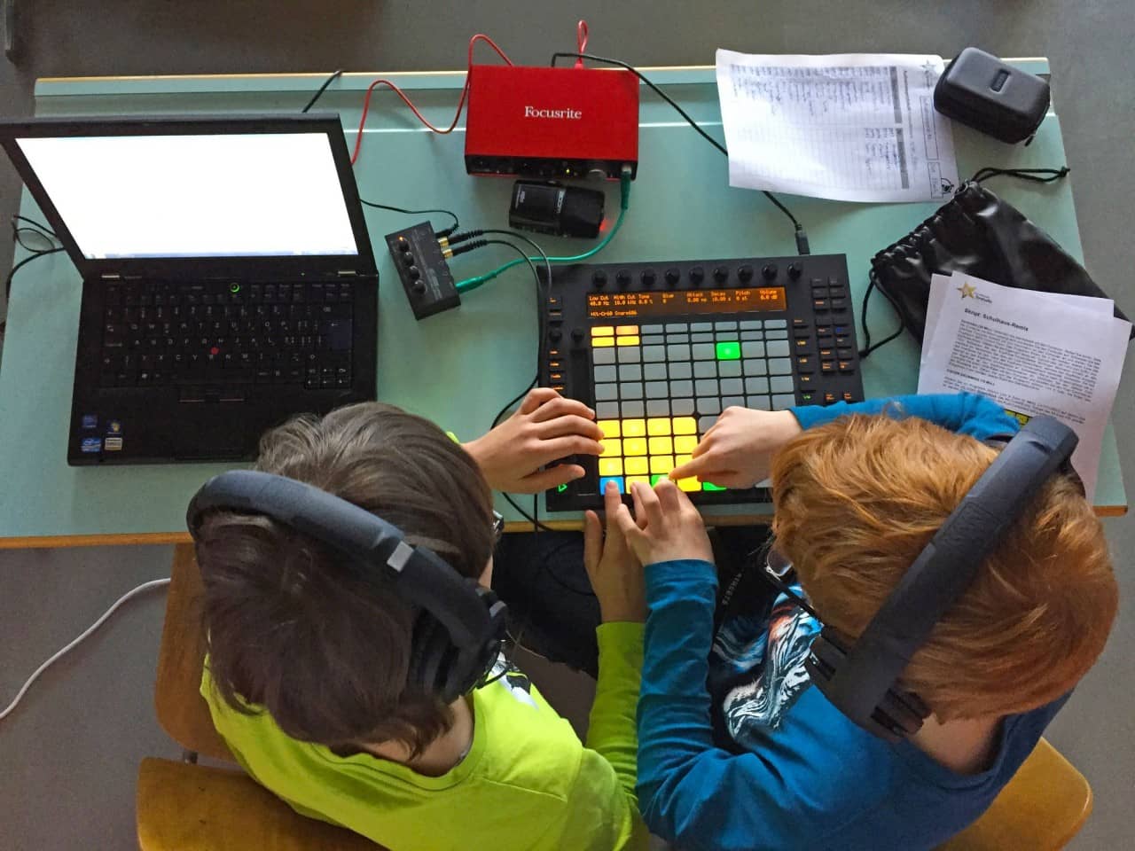 zwei Schüler sitzen vor hantieren mit einem Controller und einem Laptop