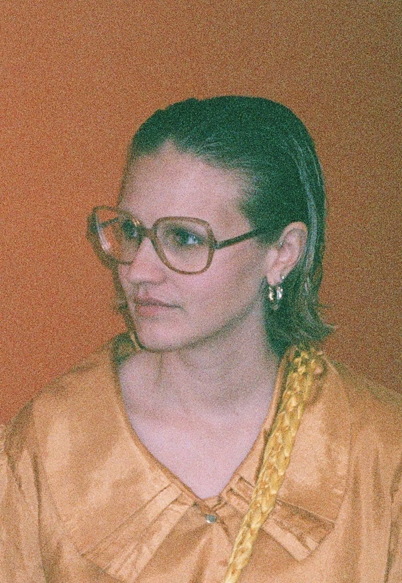 Portrait einer jungen Frau mir Brille und blonden Haaren.
