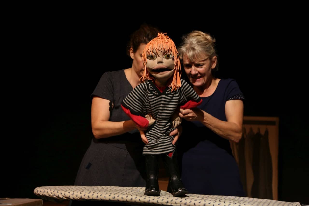 Zwei Schauspielerinnen bewegen eine weibliche Figur.