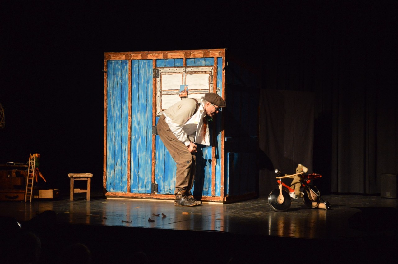 Ein Mann befindet sich auf einer Bühne und spricht mit einem Hasen.