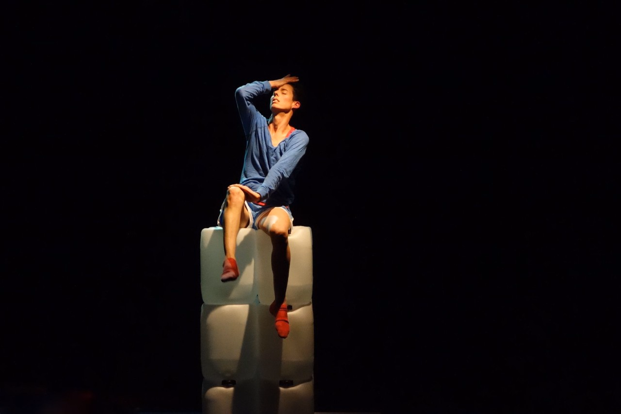 Eine Frau sitzt auf der Bühne.