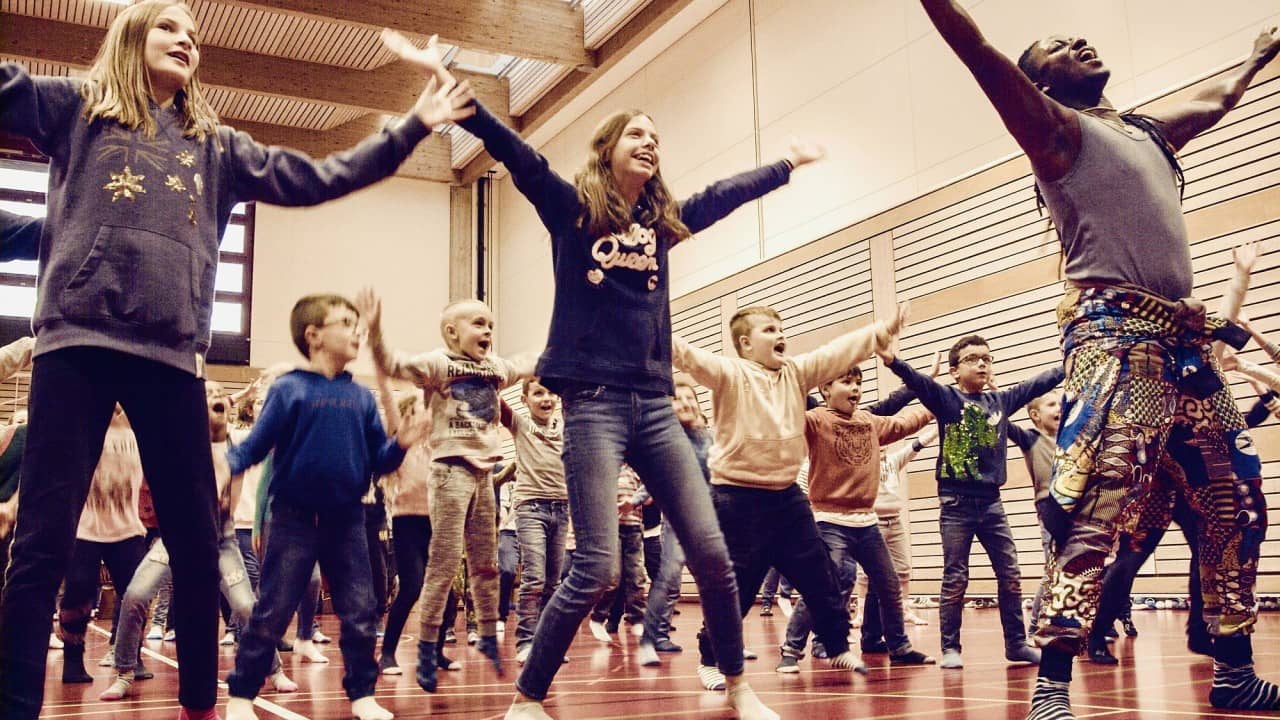Ein Tänzer und Schülerinnen und Schüler in Bewegung 