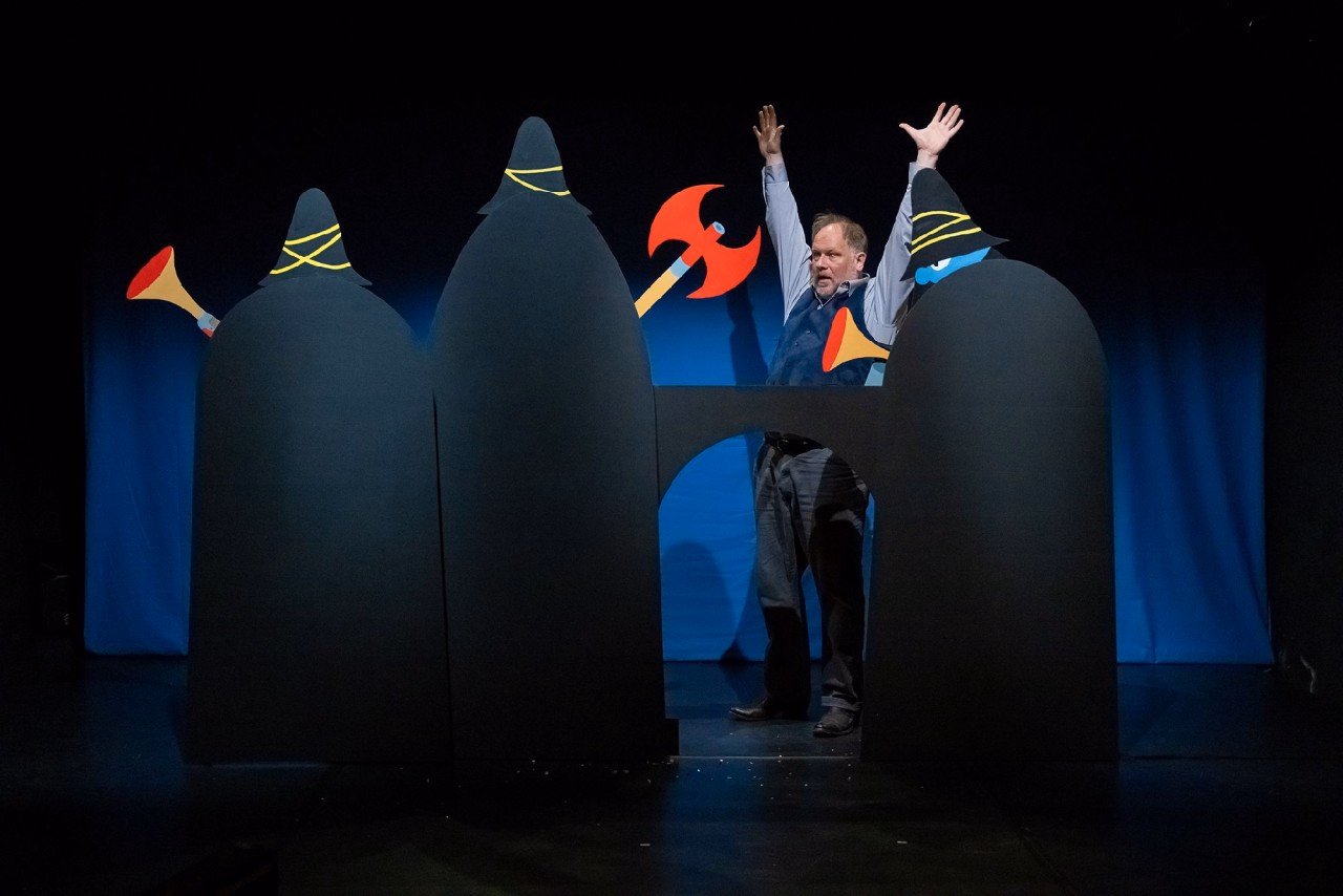 Ein Mann hält die Hände hoch. Er wird von Räuberfiguren umzingelt.