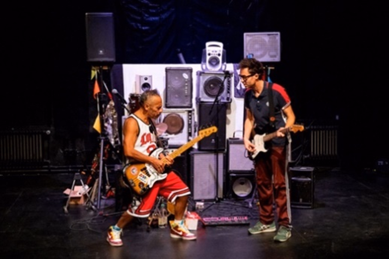 Zwei Personen befinden sich auf einer Bühne und musizieren.