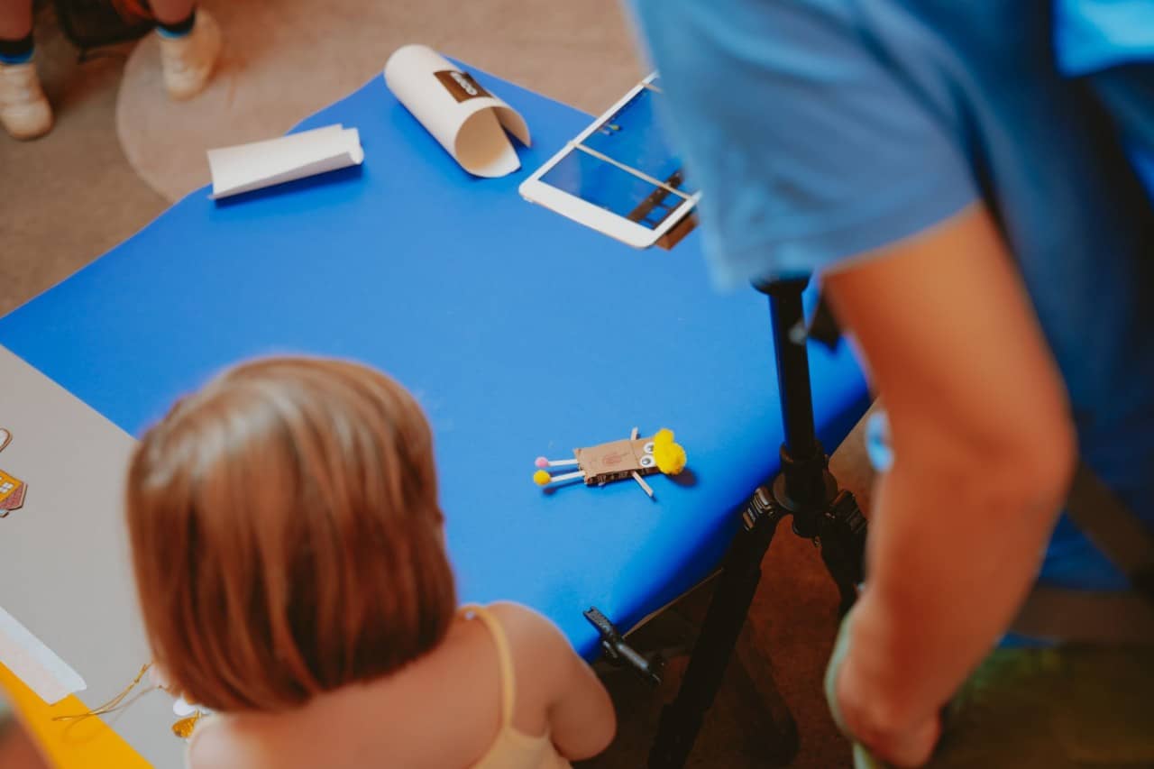 Ein mit blauem Papier eingekleideter Tisch. Darauf eine kleine Figur aus Karton.