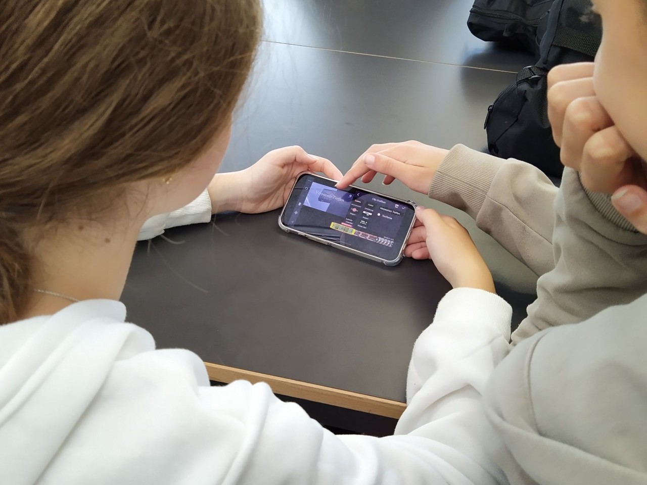 Zwei Schülerinnen bedienen ein Überarbeitungsprogramm auf dem Smartphone.