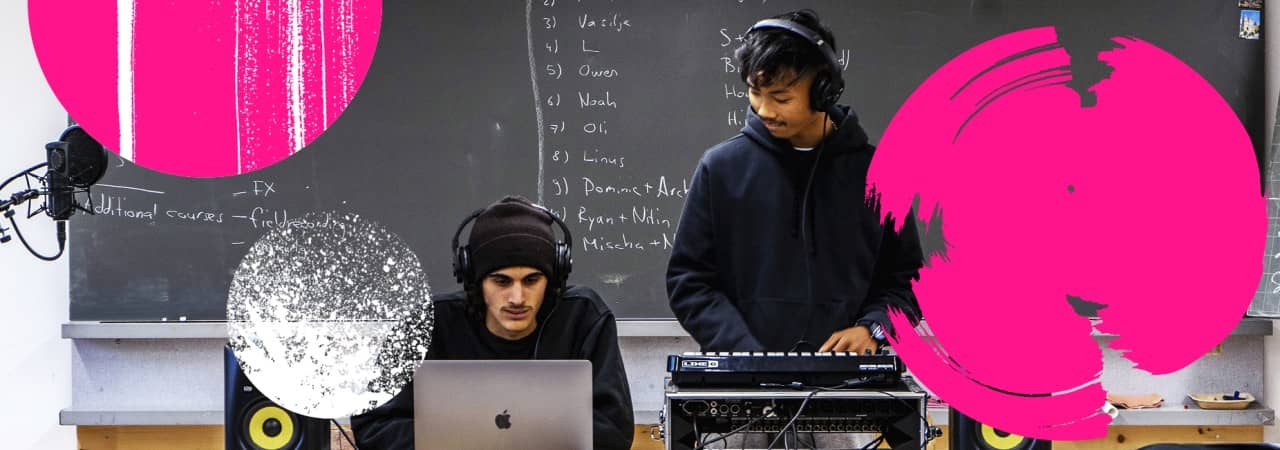 Zwei Schüler sitzen an einem Laptop und einem Mischpult. Im Hintergrund ist eine Wandtafel.