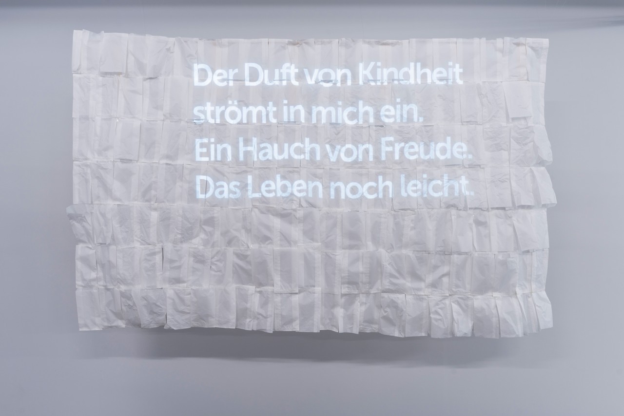 Weisser Prosatext auf einem knittrigen weissen Papier vor weissem Hintergrund.