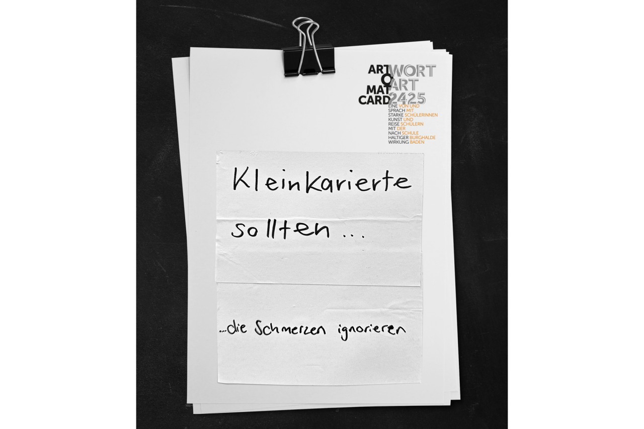 Zusammengeklammerte weisse Blätter mit von Hand geschriebenem Satz "Kleinkarierte sollten... die Schmerzen ignorieren" .