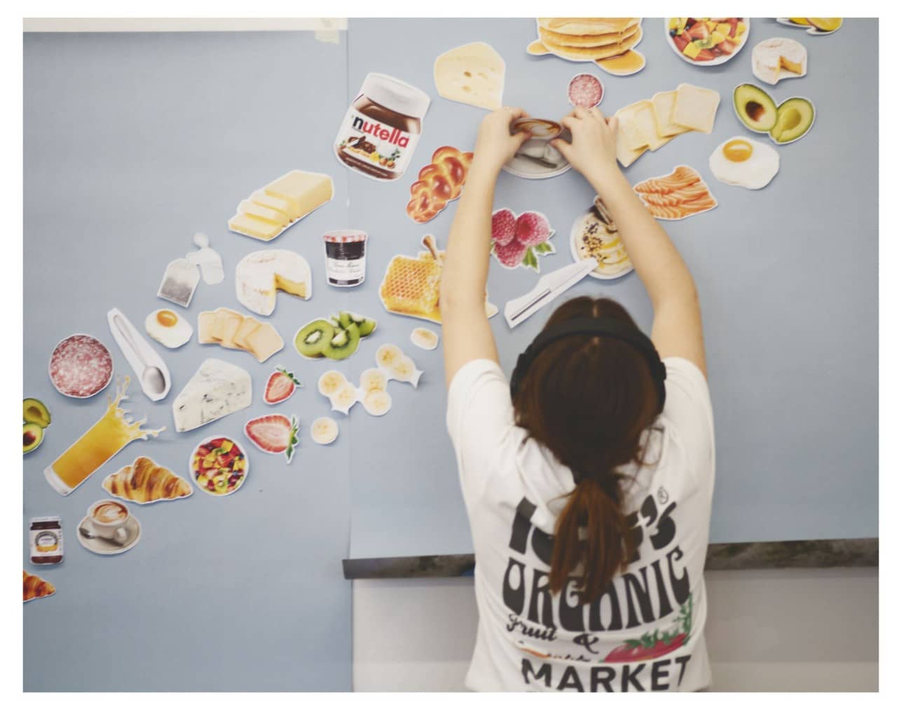 Mädchen klebt Lebensmittelbilder an die Wand