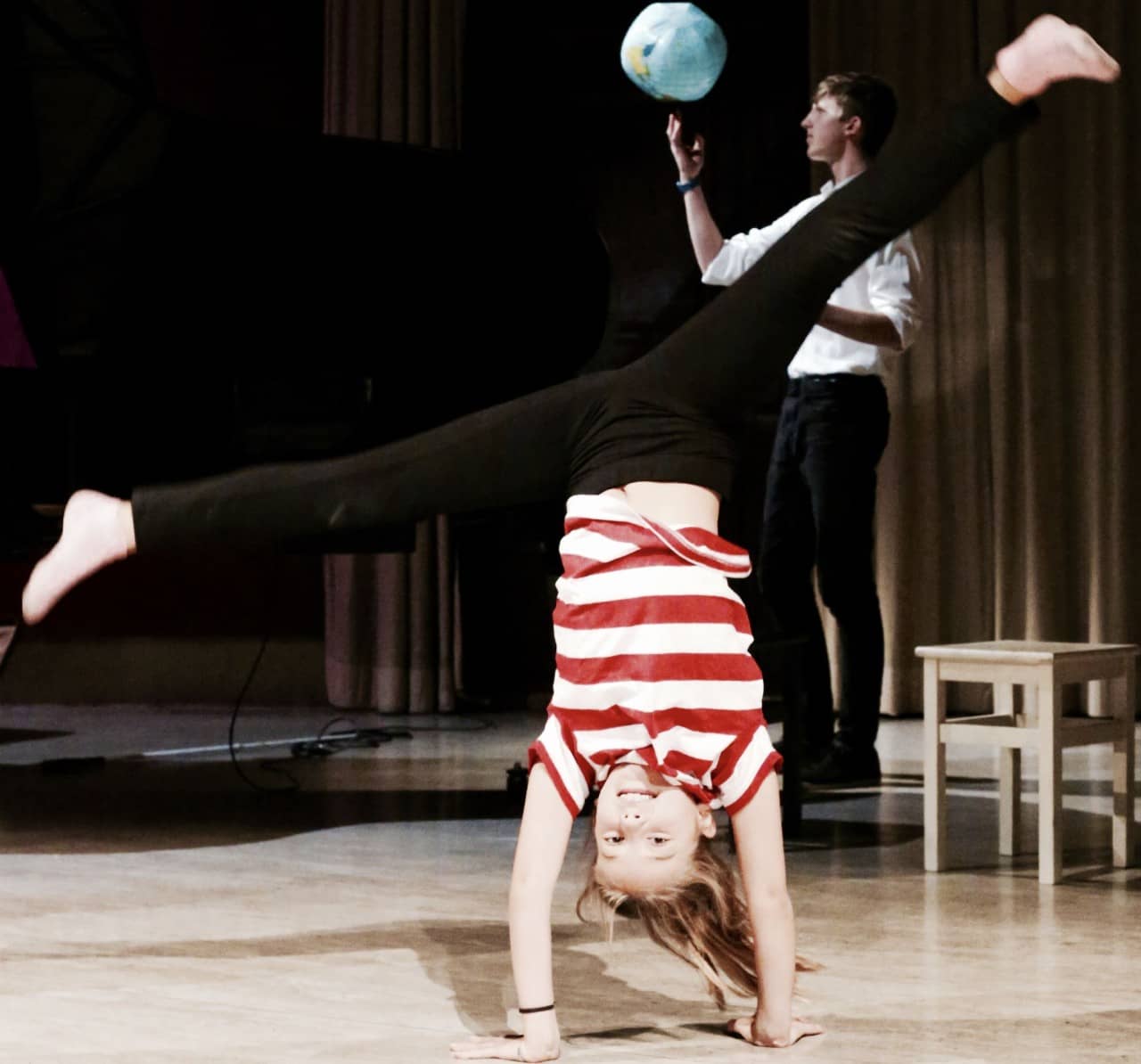 Mädchen macht Handstand und Junge jongliert mit einem Ball.