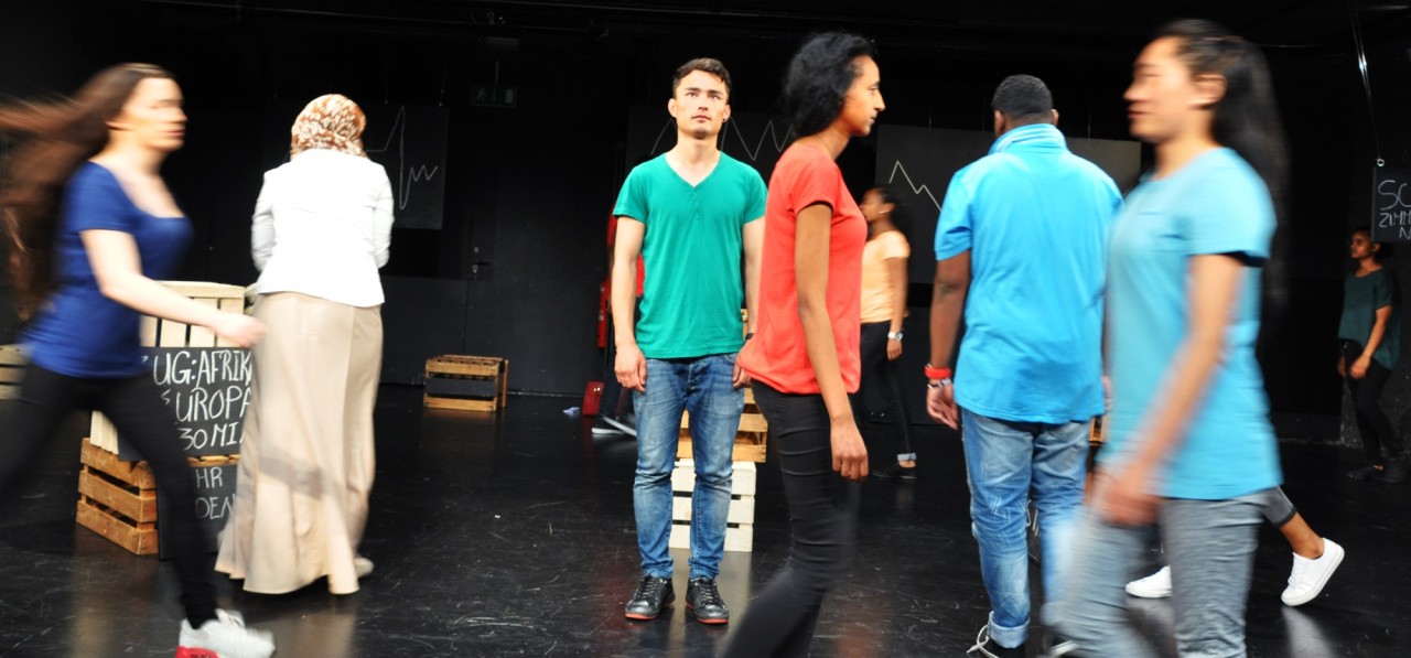 Junge Menschen bewegen sich durch einen Theaterraum.