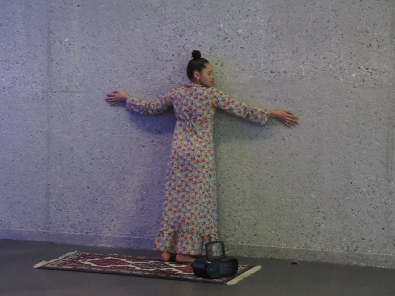 Ein Mädchen steht mit ausgestreckten Armen vor einer Wand.