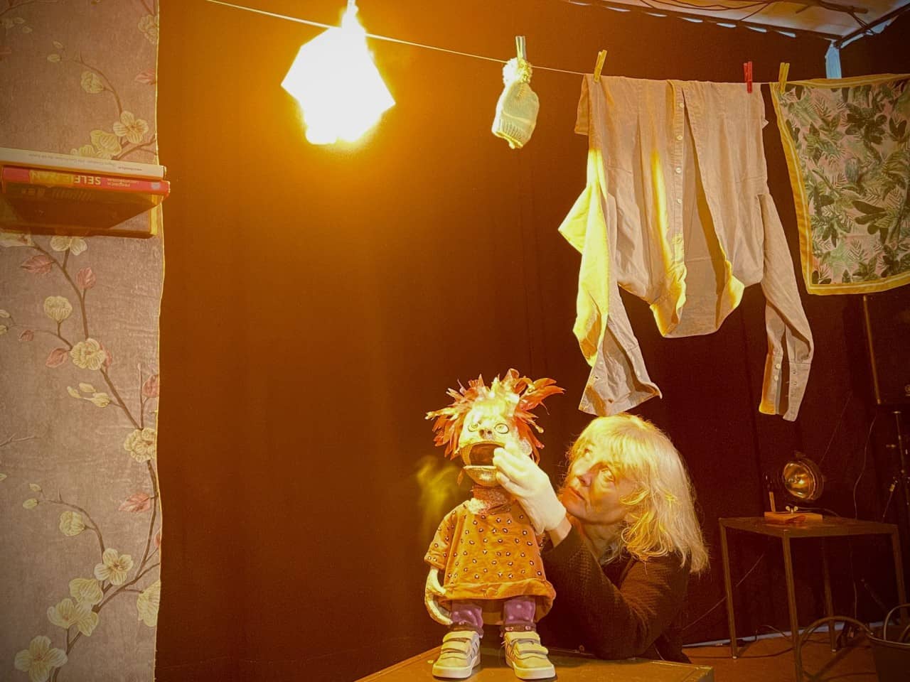 Eine Schauspielerin und eine Puppenfigur schauen zu einer Flamme hoch