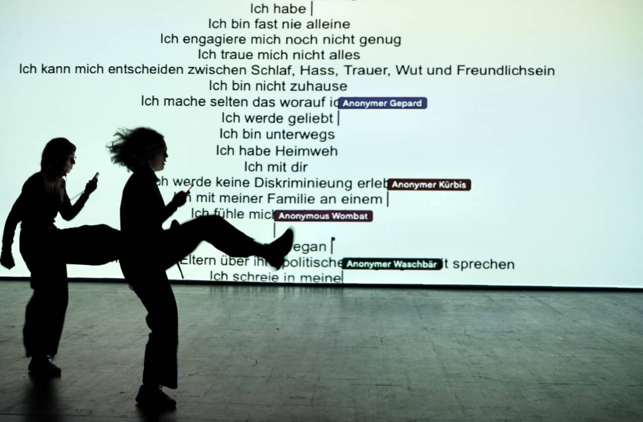 Zwei Jugendliche mit Smartphone in der Hand machen grosse Schritte über die Bühne