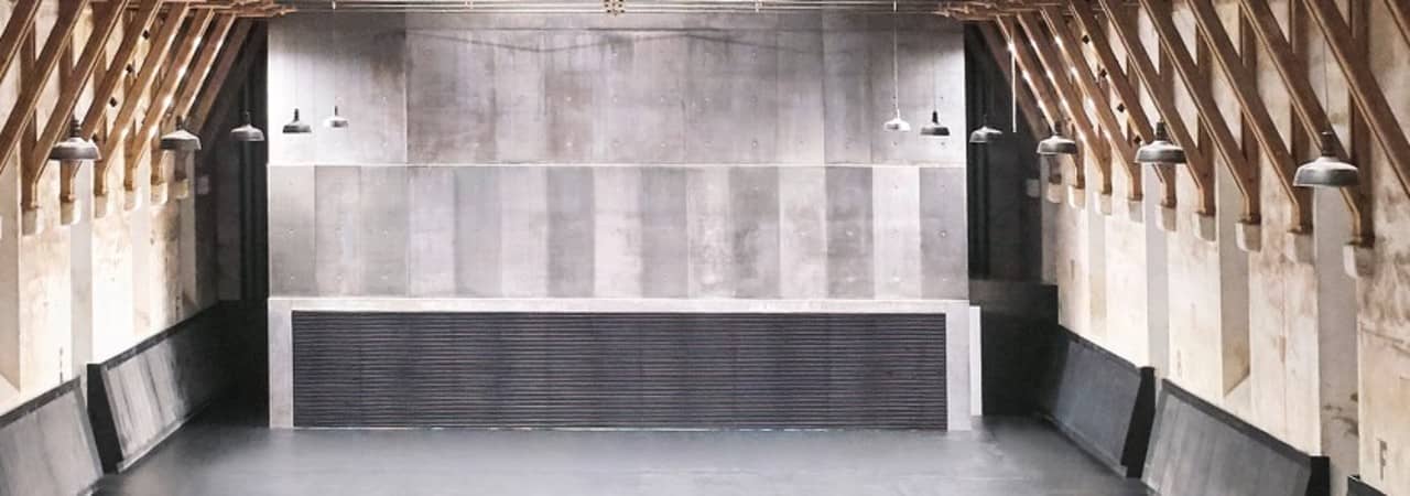 Sechs Personen kauern im Vordergrund und schauen frontal aus dem Foto. Im Hintergrund sind ansatzweise sieben weitere Personen zu sehen.