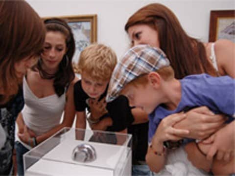 Children looking at a ball inside a display case of glass