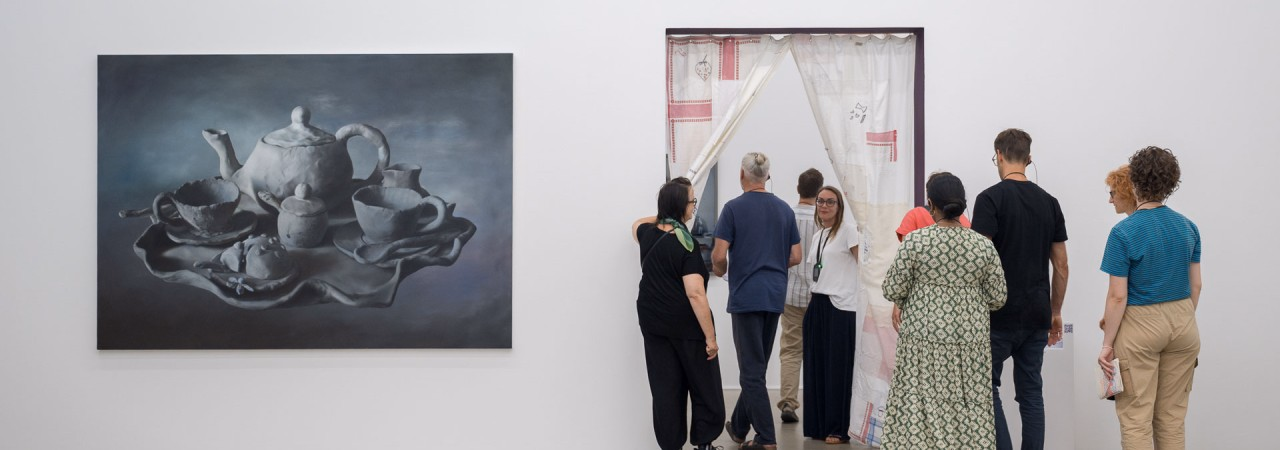 Erwachsene Besuchende laufen durch eine Türe neben einem Ölgemälde im Aargauer Kunsthaus.