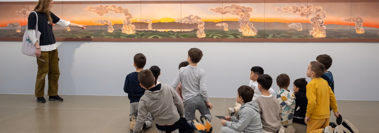 Eine Vermittlungsperson erklärt einer Schulklasse ein Kunstwerk.