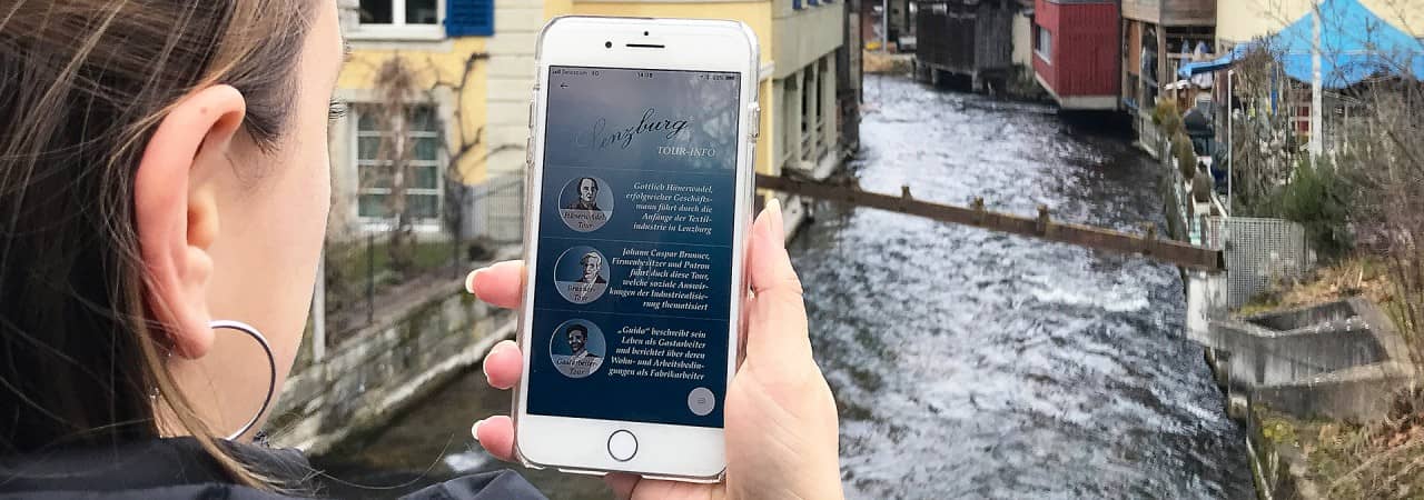 Eine Frau steht mit Handy an einem Fluss