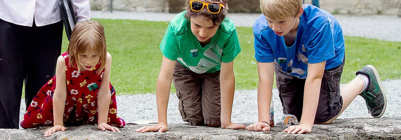 Kinder schauen von einer Mauer in den Schlossgraben