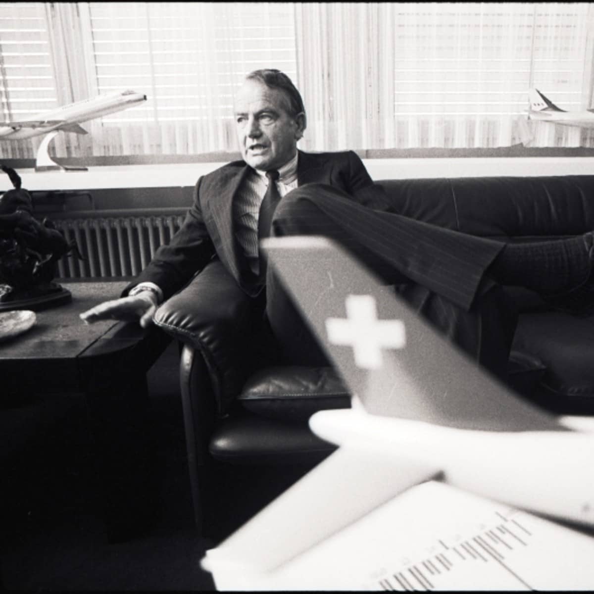 Armin Baltensweiler (Direktions-Präsident Swissair) sitzt ins seinem Büro, im Vordergund ein Modell eines Swissair-Flugzeuges. 