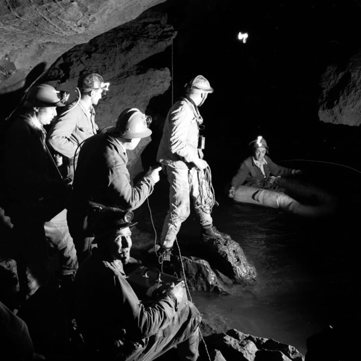 Eine Gruppe von Höhlenforschern befndet sich unter der Erde an einem unterirdischen See. 