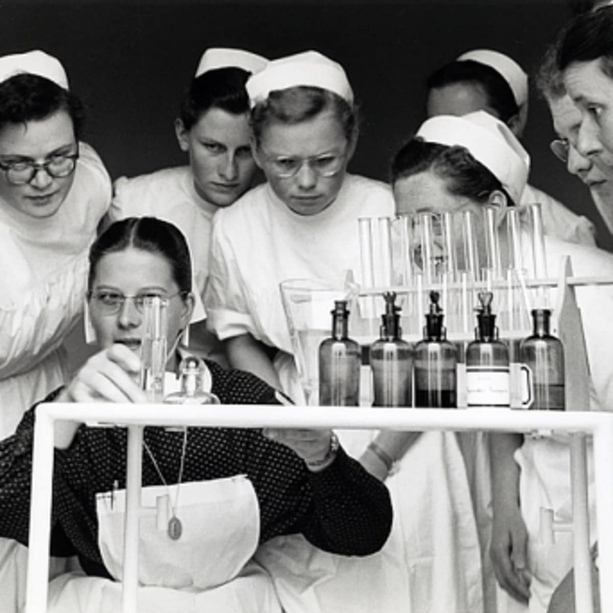 Eine Gruppe von Krenkenschwestern beim Betrachten eines medizinischen Experiments. 