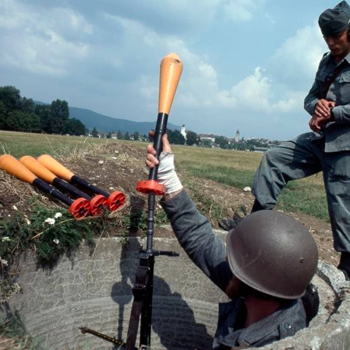 Zwei Soldaten auf einem Feld bei einer Infanterie Übung, einer von beiden sieht auf die Uhr.