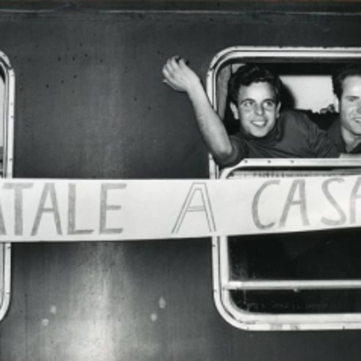 Italienische Gastarbeiter halten ein Transparent mit der Aufschrift „Natale a casa“ aus einem Zugfenster. 