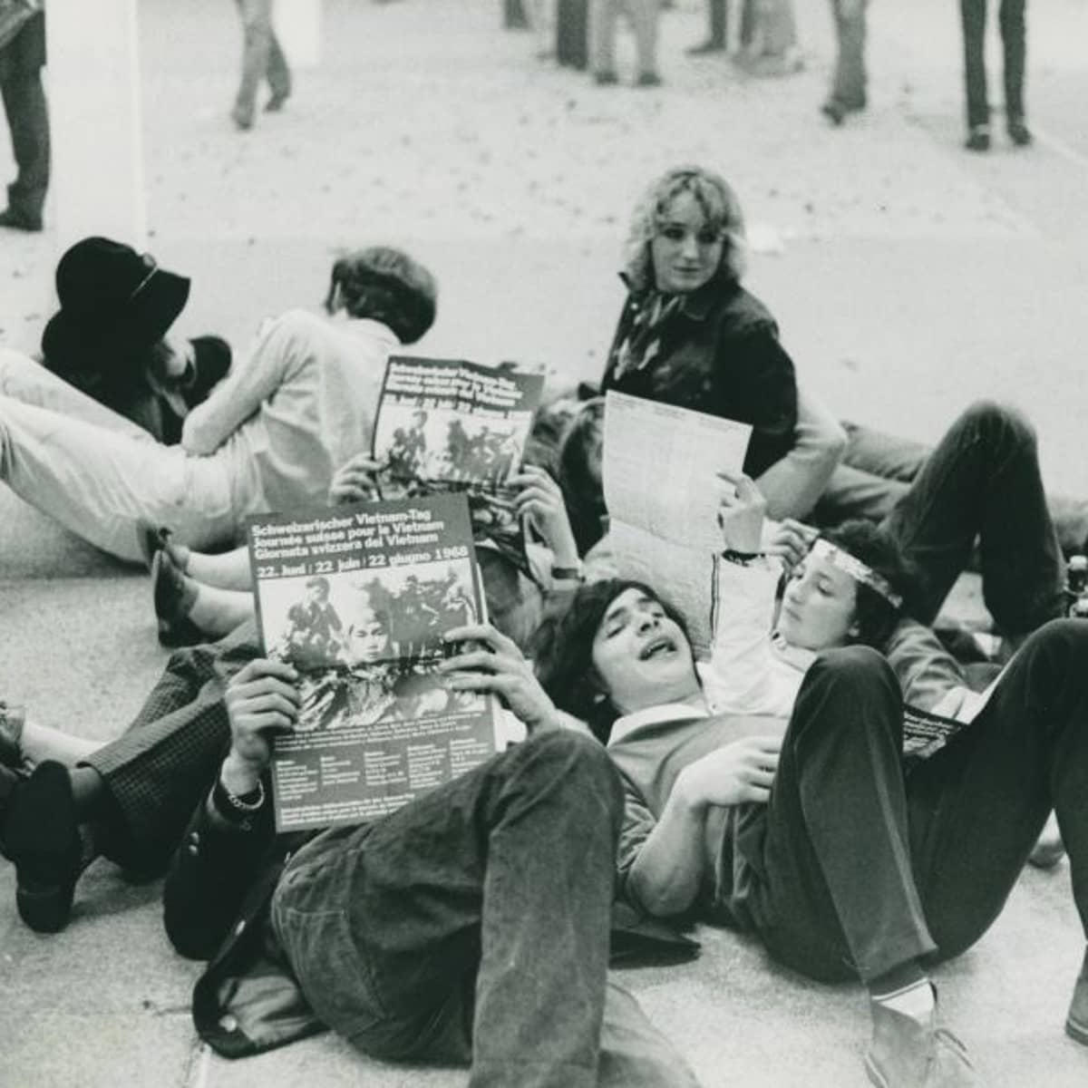 Eine Gruppe von Jugendlichen liegt am Boden und liest Broschüren zum Schweizerischen Vietnam-Tag 1968.