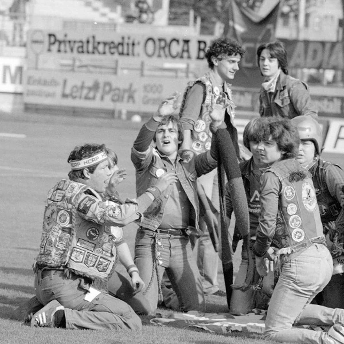 Eine Gruppe Fussballfans sitzt auf dem Spielfeld