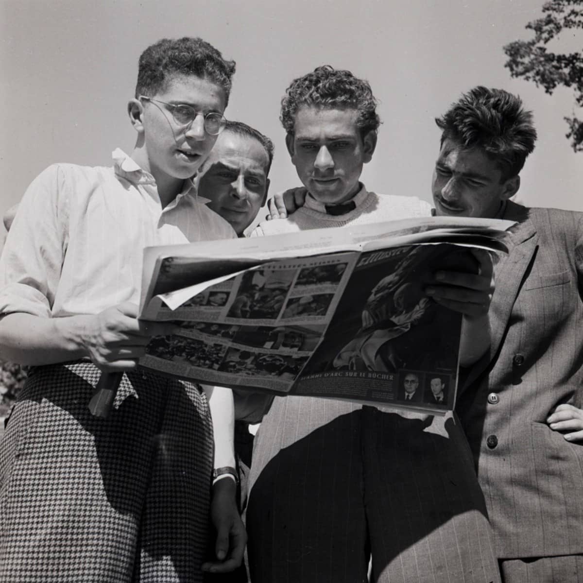 Vier Männer lesen eine Zeitschrift.