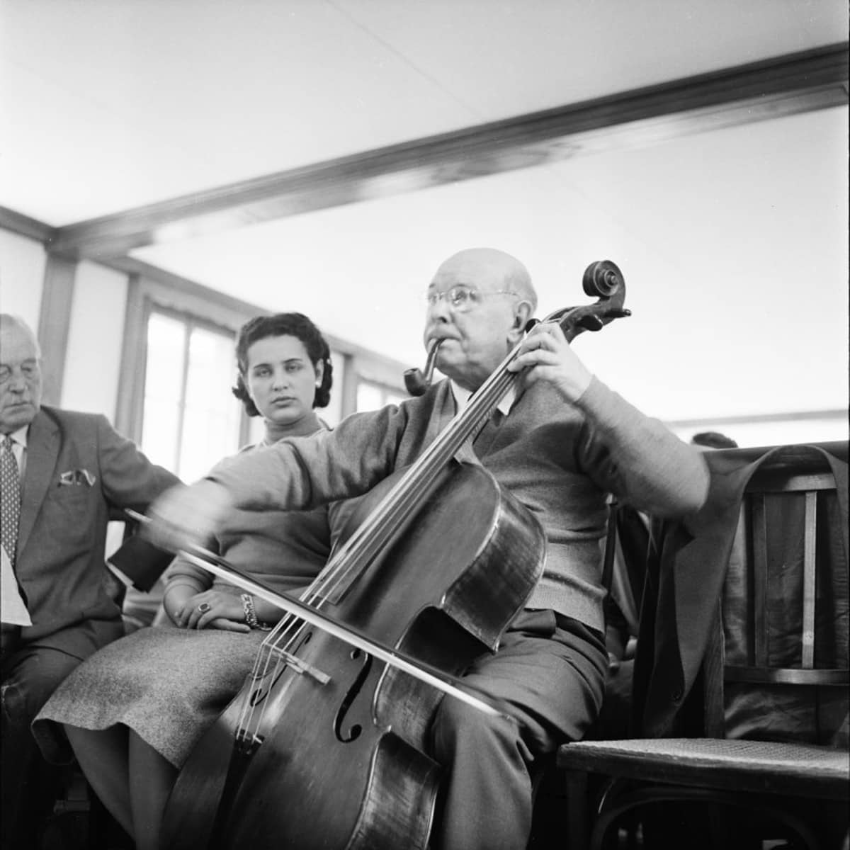 Ältere Mann spielt Cello, junge Dame schaut zu.