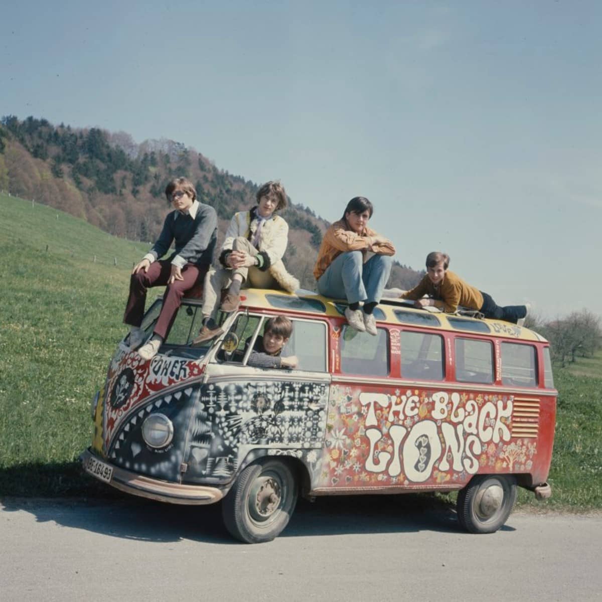 Ein bunt bemalter VW-Bus auf einer Landstrasse mit Band.