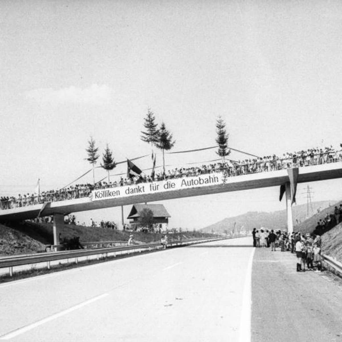 Autobahnbrücke mit Spruchband und zahlreiche Besucher auf der Brücke und an der Autobahn.