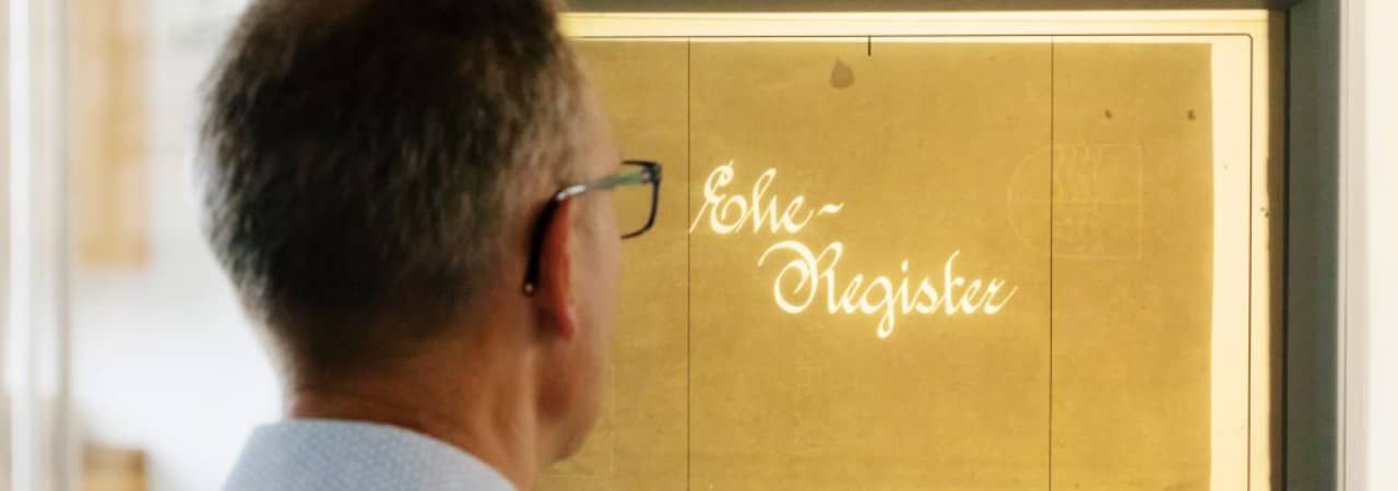 Mann schaut auf einen Bildschirm mit gelbem Hintergrund und dem Schriftzug Eheregister.