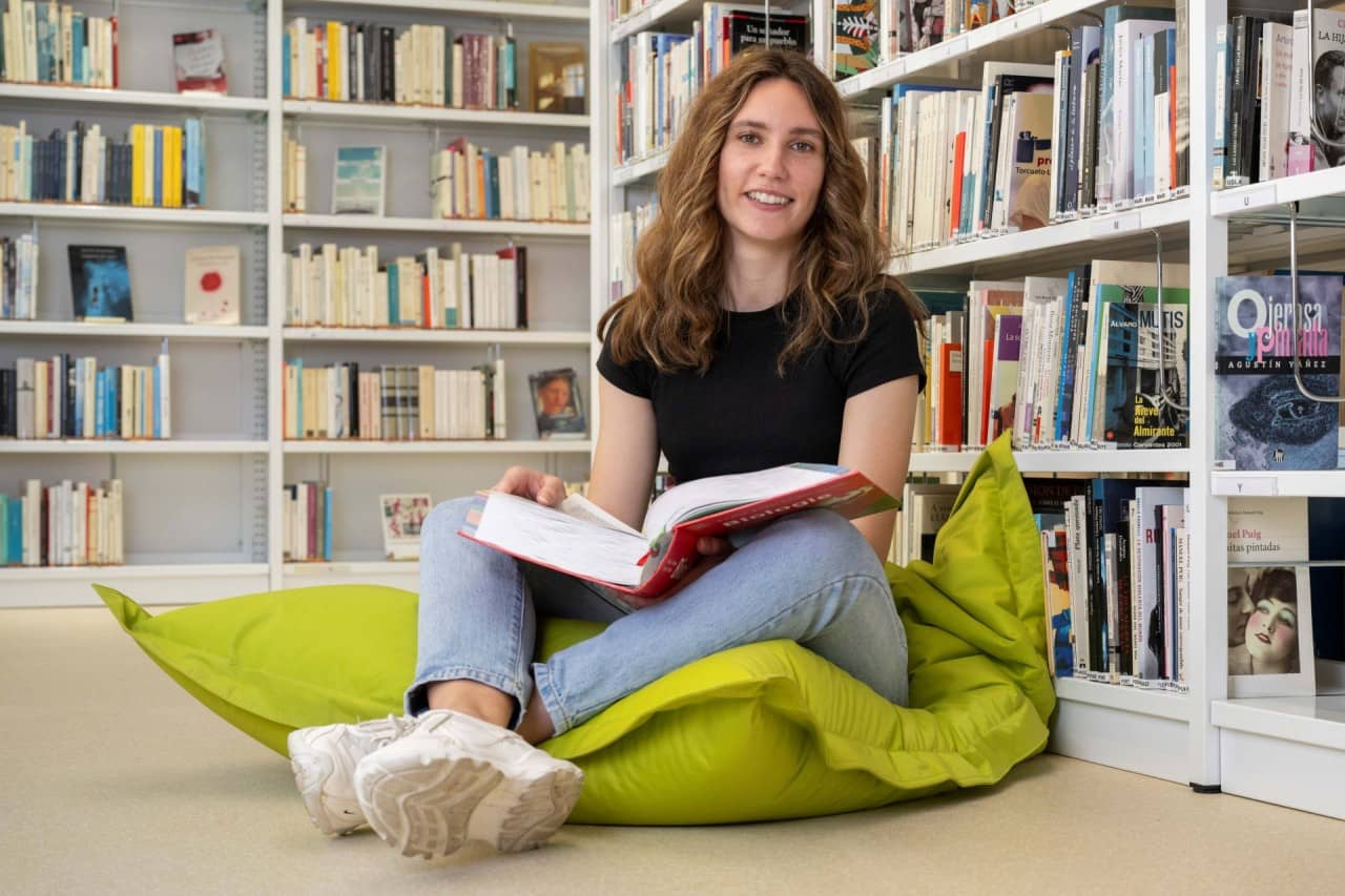 Mädchen sitzt auf Sitzsack mit Buch auf den Beinen.