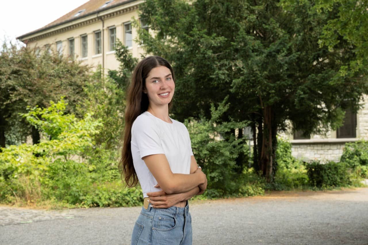 Mädchen mit verschränkten Armen steht auf Kiesweg.