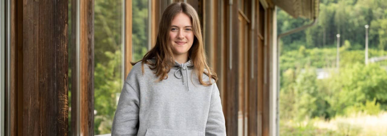 Mädchen steht auf Kiesweg neben Holzpfosten