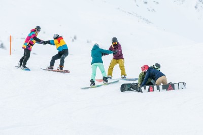 Sechs Snowboardfahrerinnen und Snowboardfahrer üben im Schnee den Walzer.