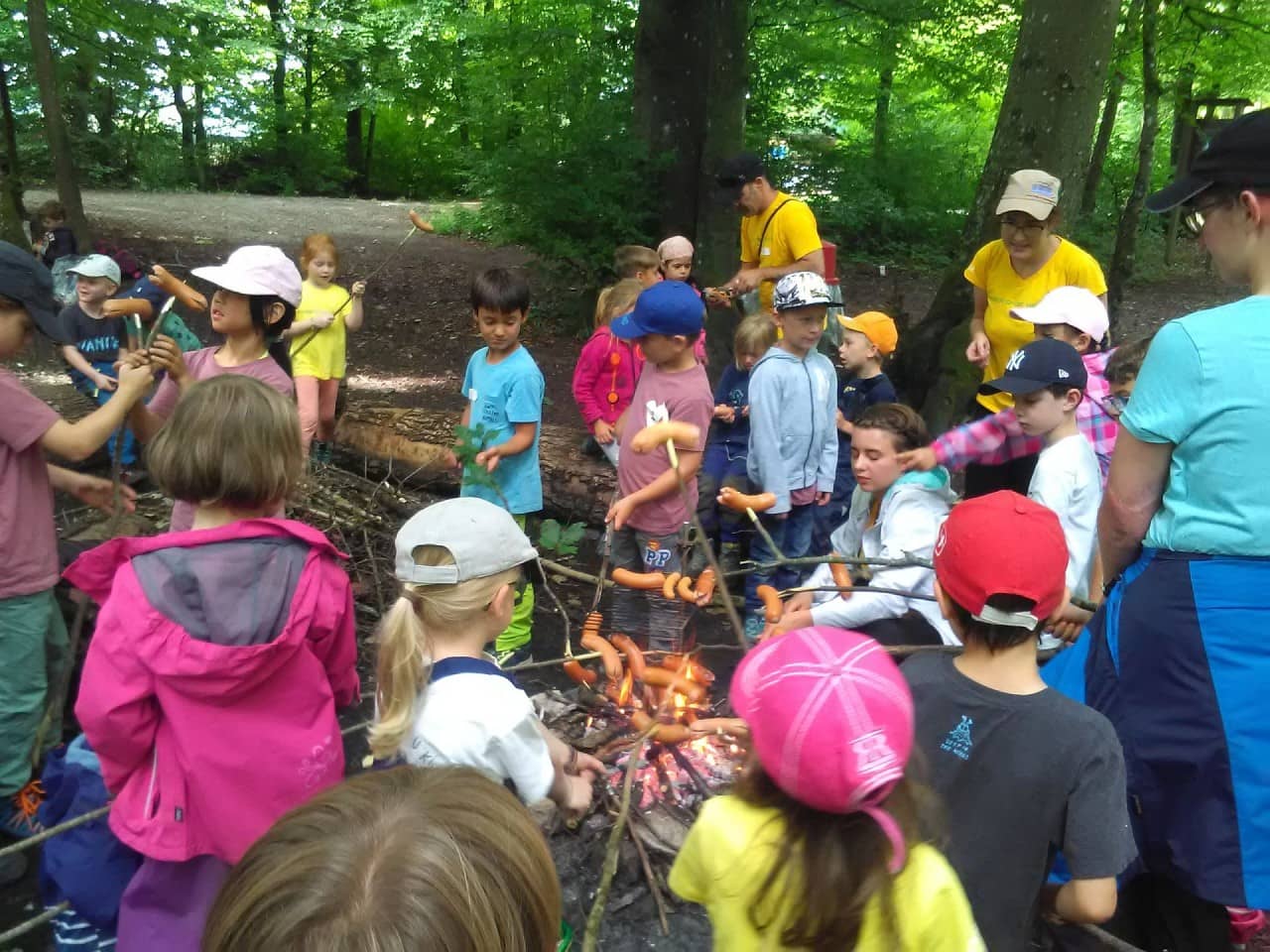 Kinder braten eine Wurst über dem Feuer