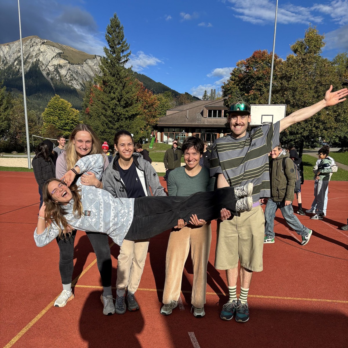 Fünf Personen posieren auf dem Sportplatz.