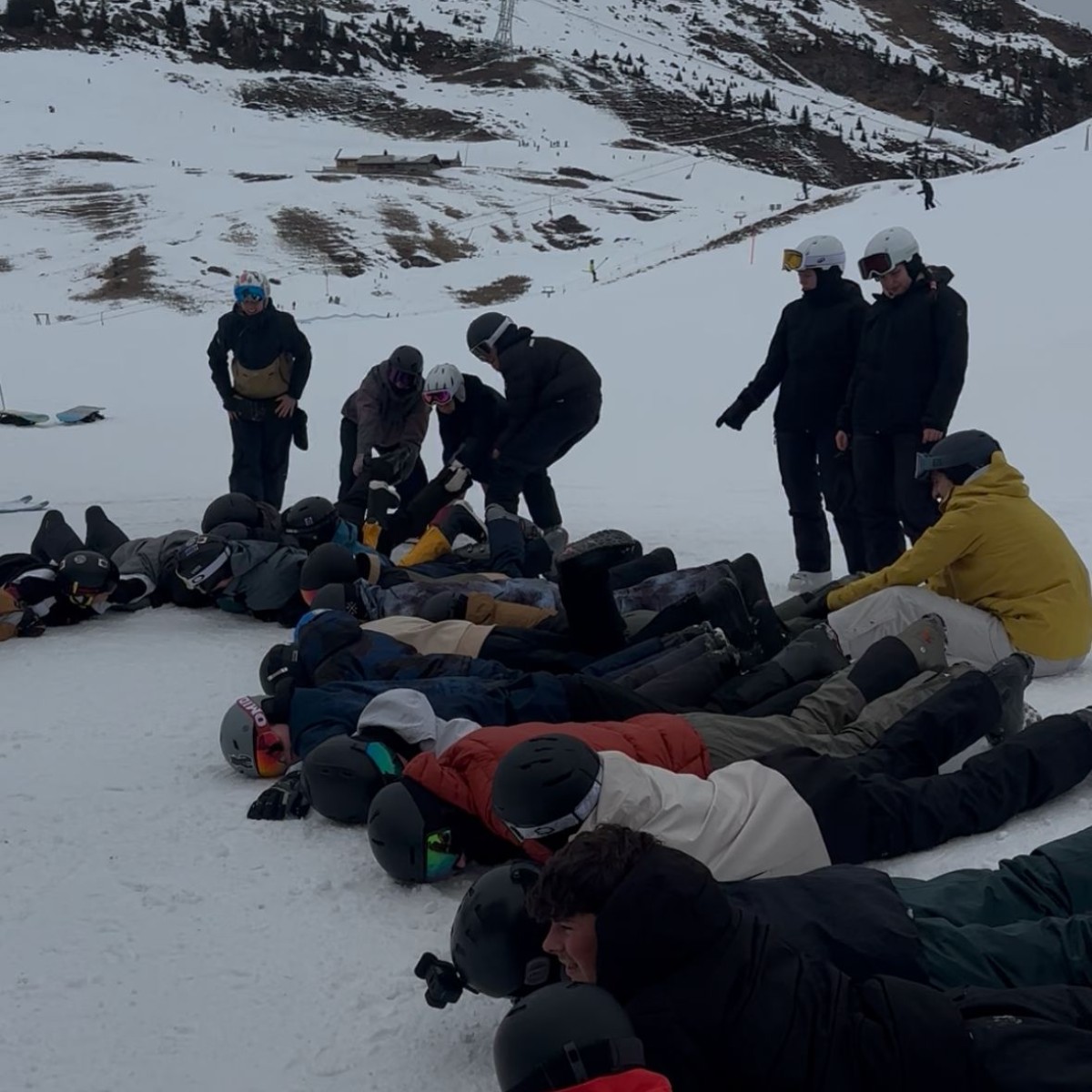 Viele Personen liegen und spielen zusammen im Schnee.