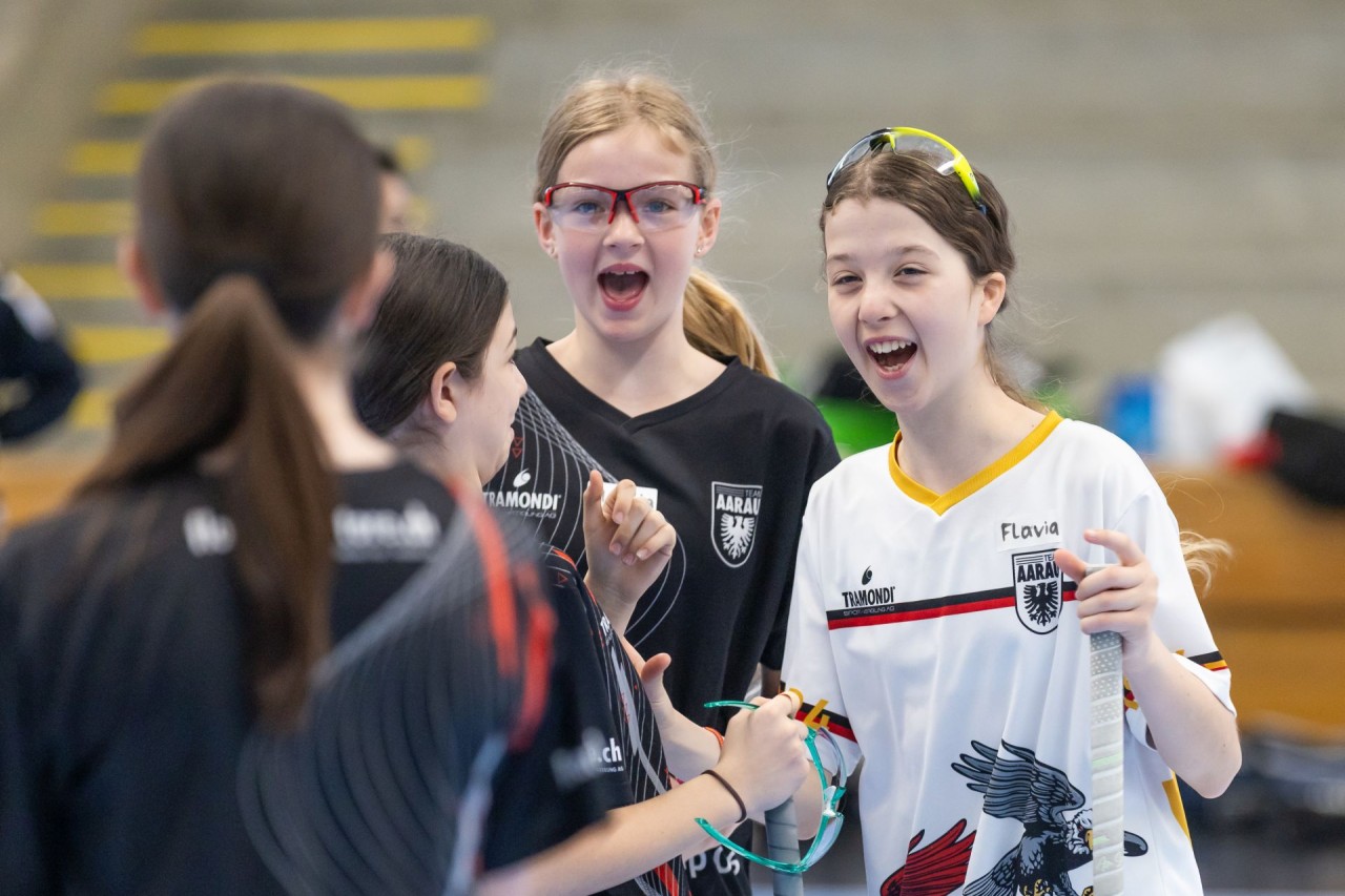Unihockeyspieldende Mädchen stehen zusammen und jubeln.
