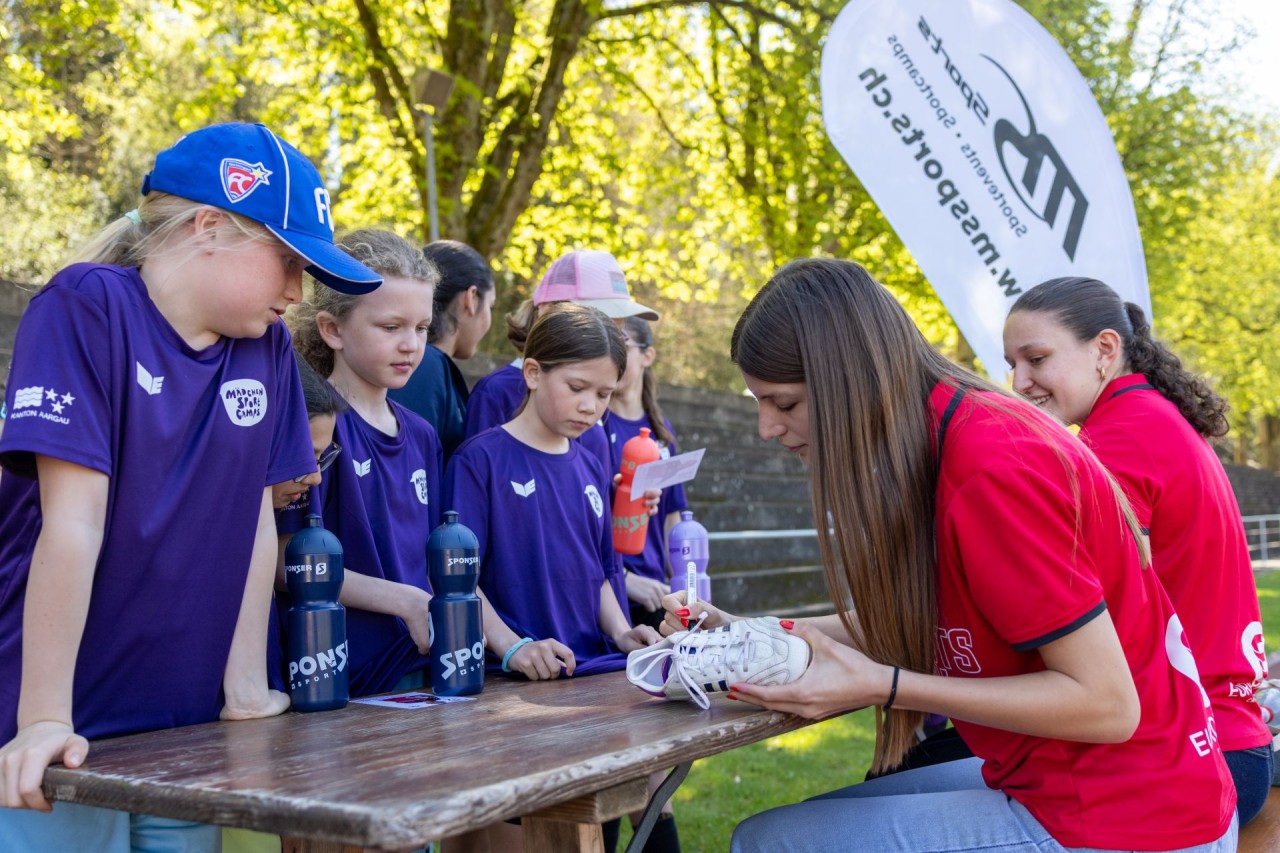 Junge Mädchen lassen sich von Fussballerinnen ein Autogramm geben.